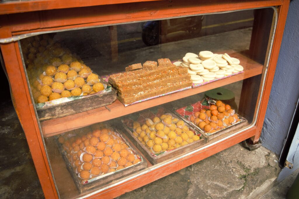 ポカラのスイーツショップ　店だな　ラドゥ（丸い団子状のもの）ほか伝統的スイーツが並ぶ