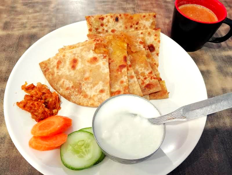 ネパール朝食の定番　アルーパラタ（じゃがいも入りの平焼きパン）＋ヨーグルト、ピクルス　ルンビニの食堂にて